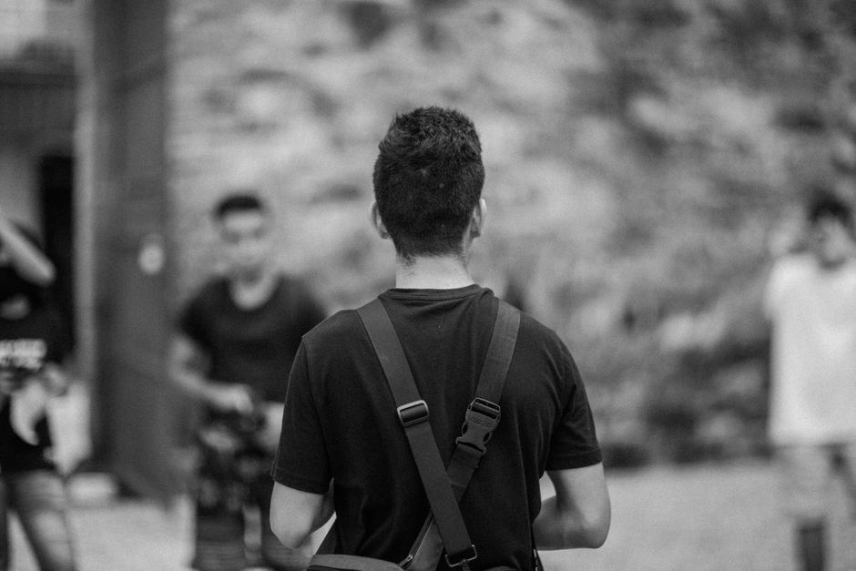 Black and white photo of people gathered outdoors from behind perspective.