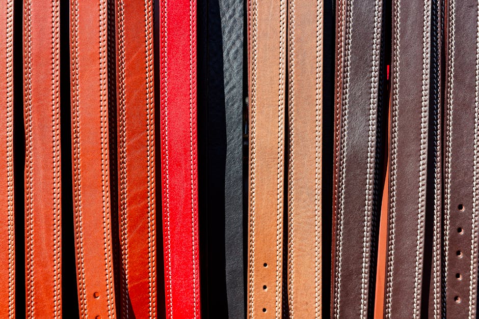 A vibrant collection of leather belts displayed vertically, showcasing various colors and textures.