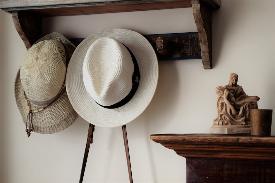 Elegant hats hanging on a wooden rack beside decorative sculpture. Perfect for rustic interior inspiration.