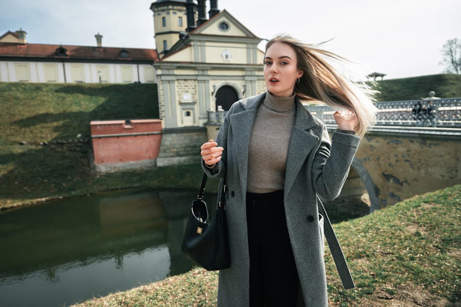 Fashionably dressed woman poses at historic Niasvizh Castle.