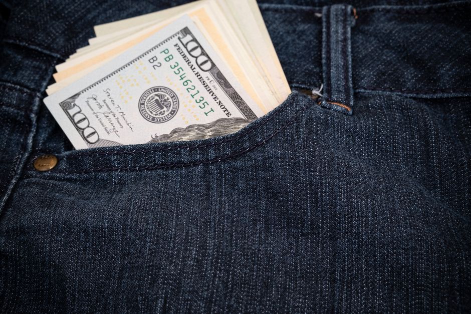 Close-up of hundred-dollar bills in a denim jeans pocket, symbolizing wealth and fashion.