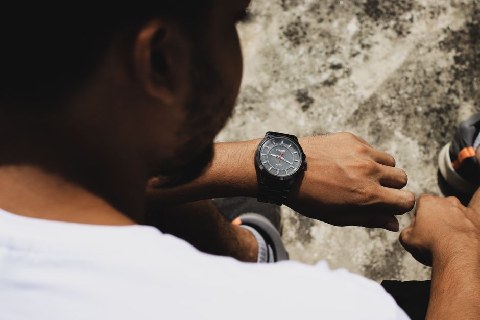 A man outdoors checking time on a stylish wristwatch, highlighting men's fashion.