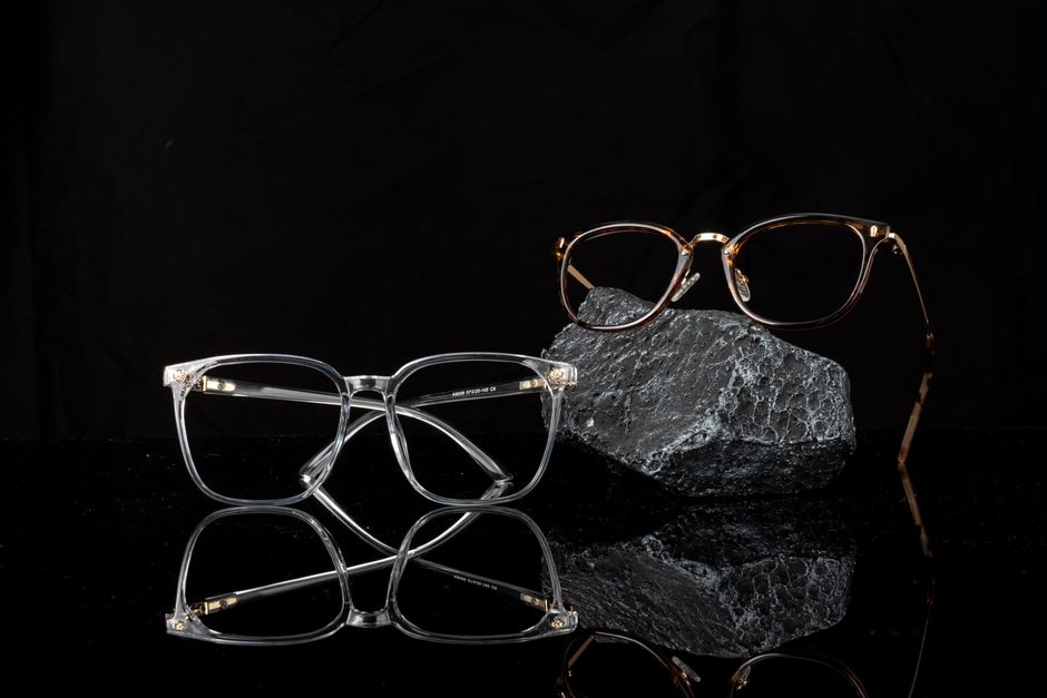 Stylish eyeglasses showcased on a reflective black surface, emphasizing modern fashion and optical design.