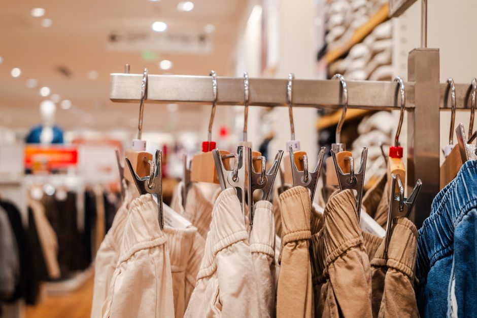 Detail shot of trousers on hangers in a clothing store, highlighting fashion trends.