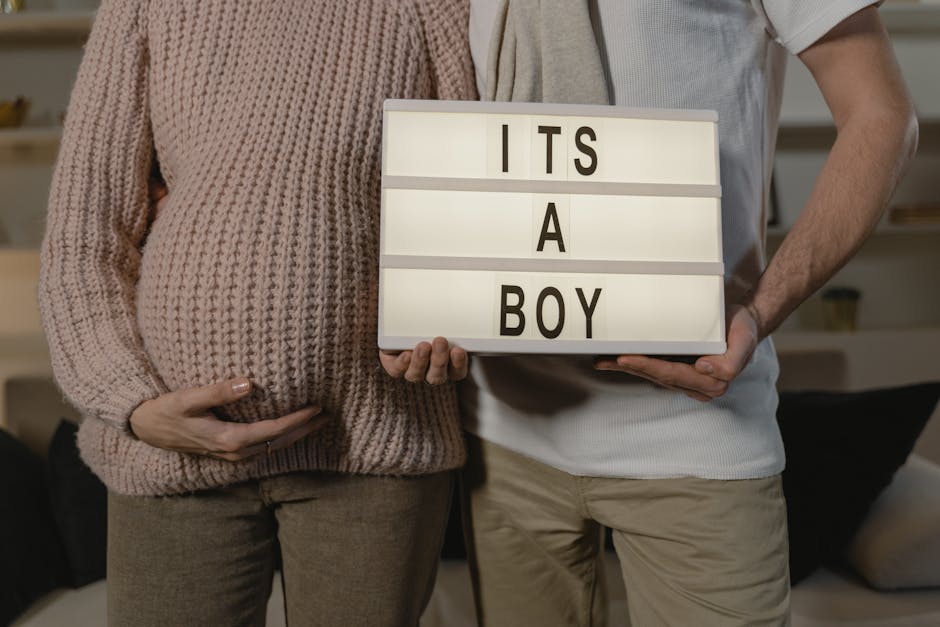 Pregnant couple indoors holding an 'It's a boy' sign, celebrating expecting a son.