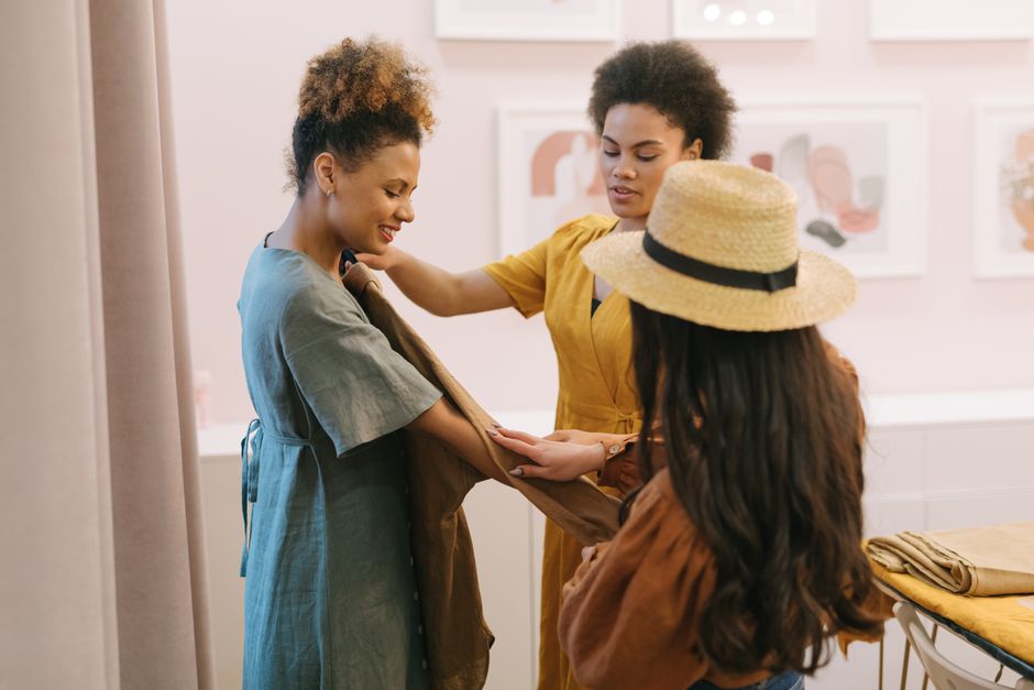 Three women collaborate in a stylish boutique, showcasing teamwork and diversity.