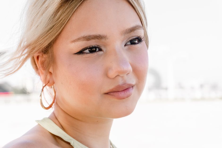 Close-up of a blonde woman with hoop earring, gazing thoughtfully in an outdoor setting.
