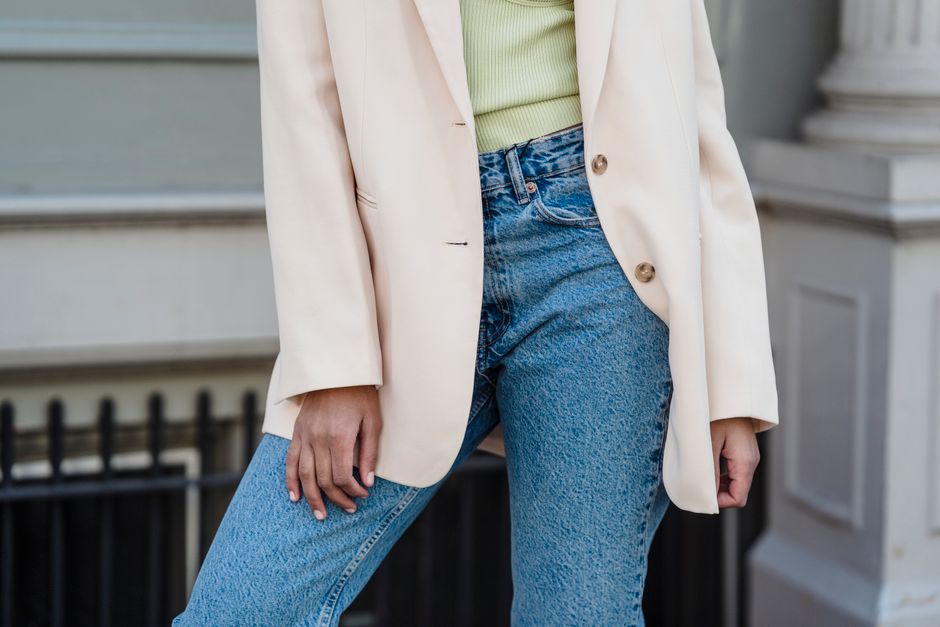 Crop anonymous trendy female in beige jacket and jeans standing in town in daylight