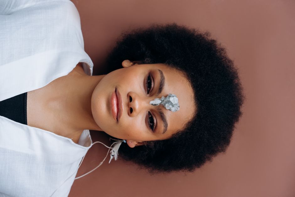 Calming portrait of a woman lying down with a healing crystal on her forehead, promoting wellness and relaxation.