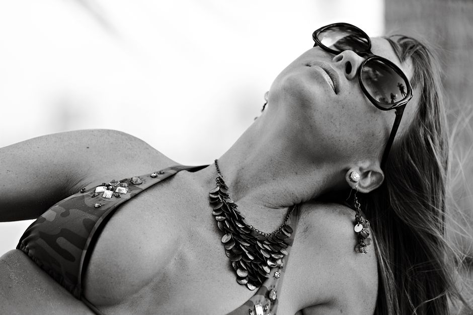 Black and white photo of a woman in sunglasses posing confidently on Miami Beach.