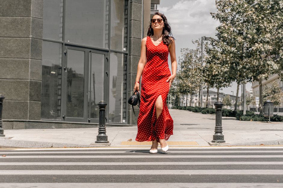 Confident woman in a red polka dot dress crossing a city street in Baku, Azerbaijan.