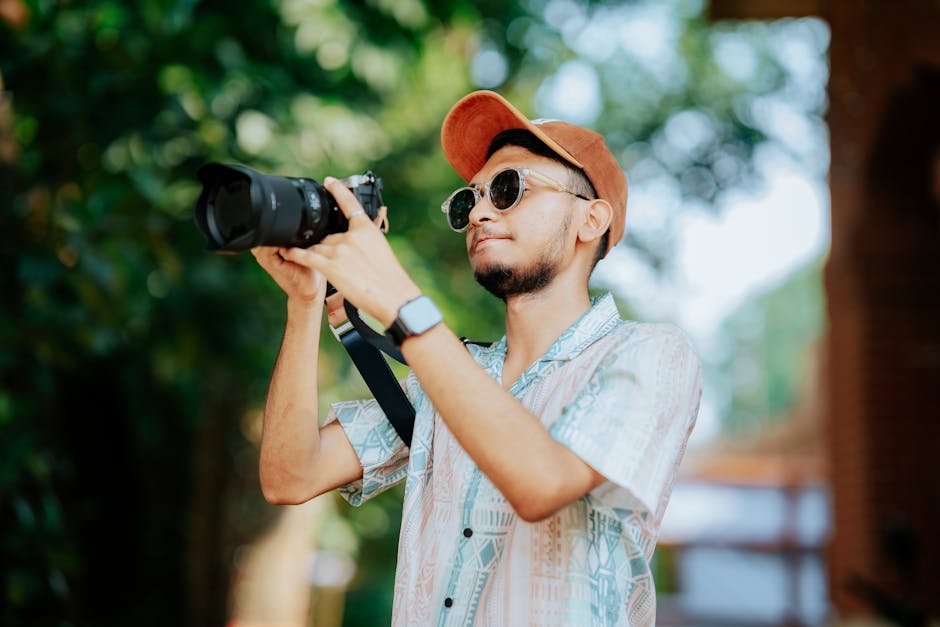 Young male photographer with camera outdoors, focusing on a scene.