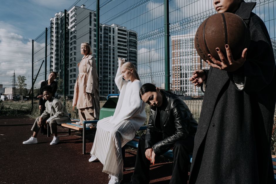 Stylish fashion models pose in urban outdoor setting with basketball.