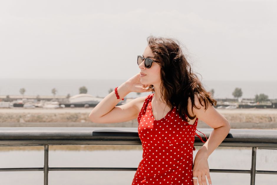 Portrait of a woman in a red polka dot dress enjoying a seaside view in Baku, Azerbaijan.