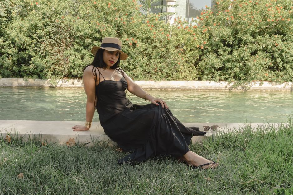 Charming woman in elegant black dress enjoying a sunny day by a stream in Baku.